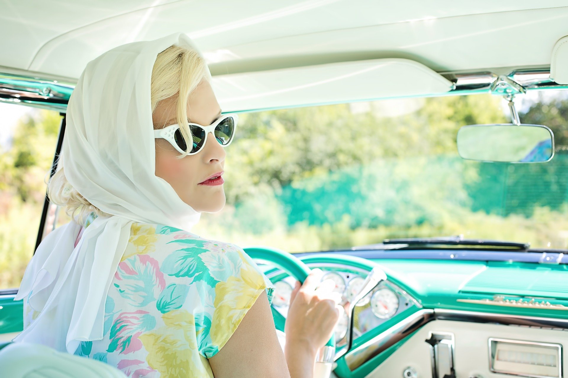 Mujer vintage conduciendo con gafas de sol y pañuelo